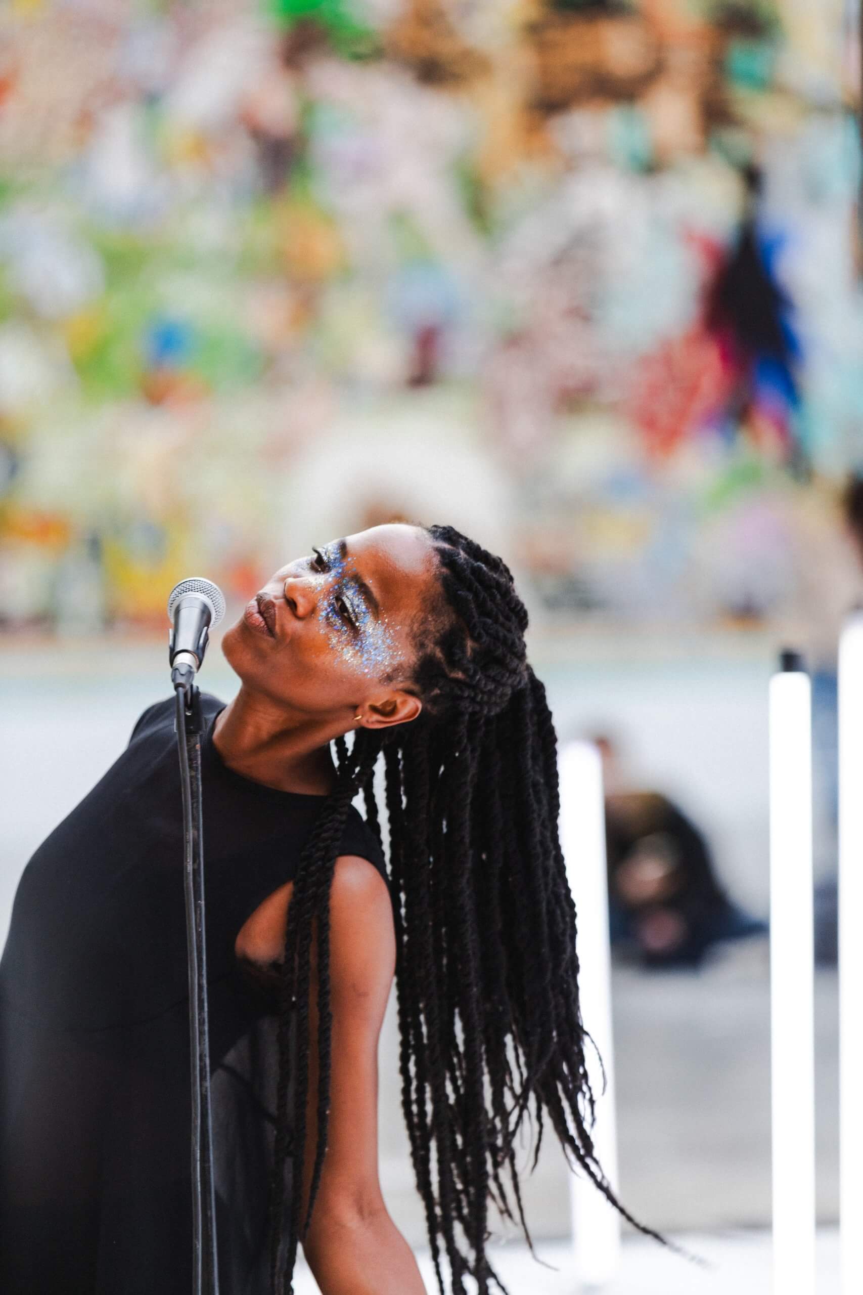 Une femme aux tresses chante dans un microphone, pleine d'énergie et d'émotion.