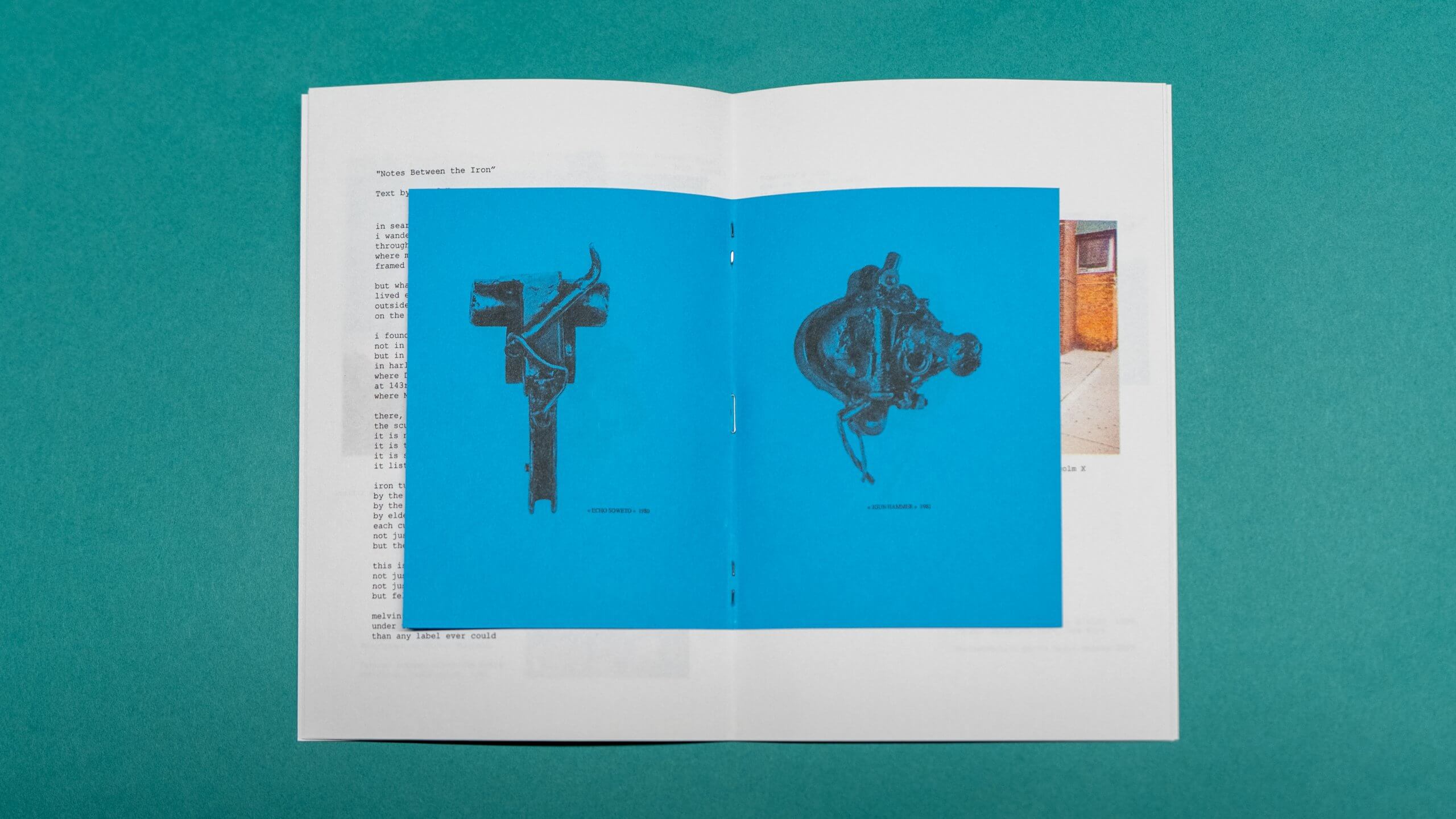 An open booklet on a teal surface displays two pages with blue backgrounds, each featuring a black mechanical object illustration.