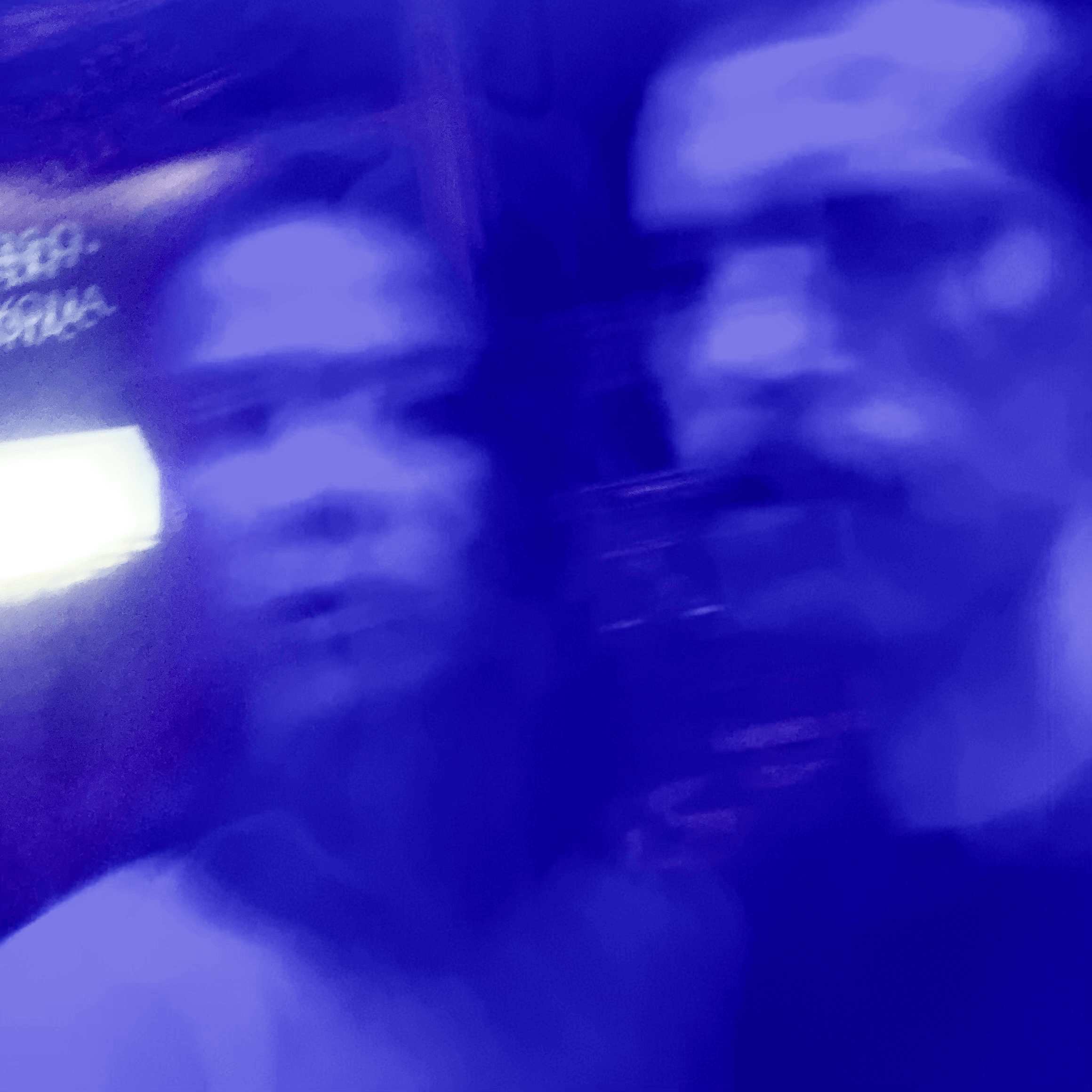 Image floue, teintée de bleu, de deux personnes proches l'une de l'autre, dont les visages sont indistincts et partiellement confondus en raison du flou de mouvement.