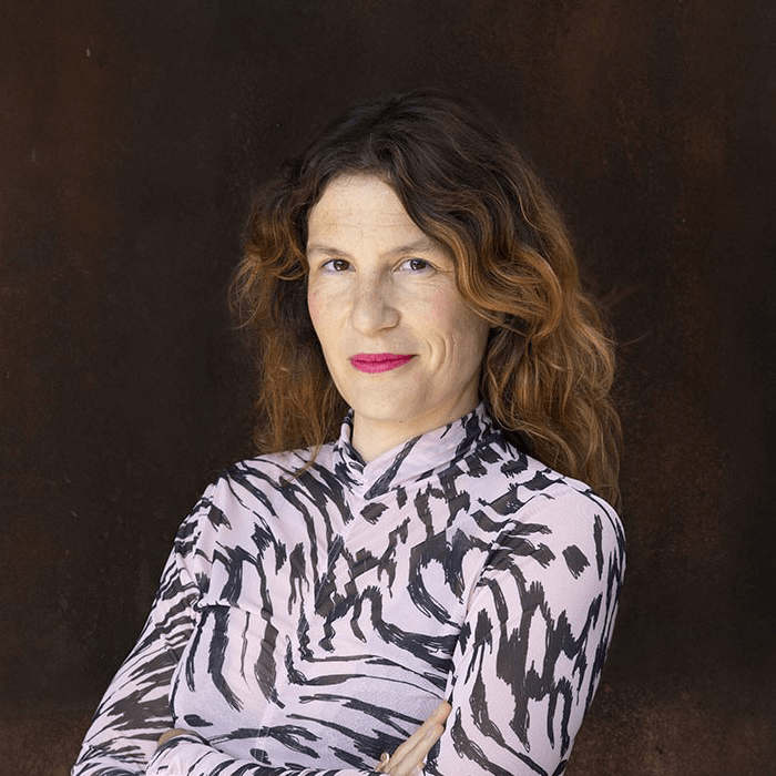 Une femme aux longs cheveux bruns portant une chemise rose et noire.