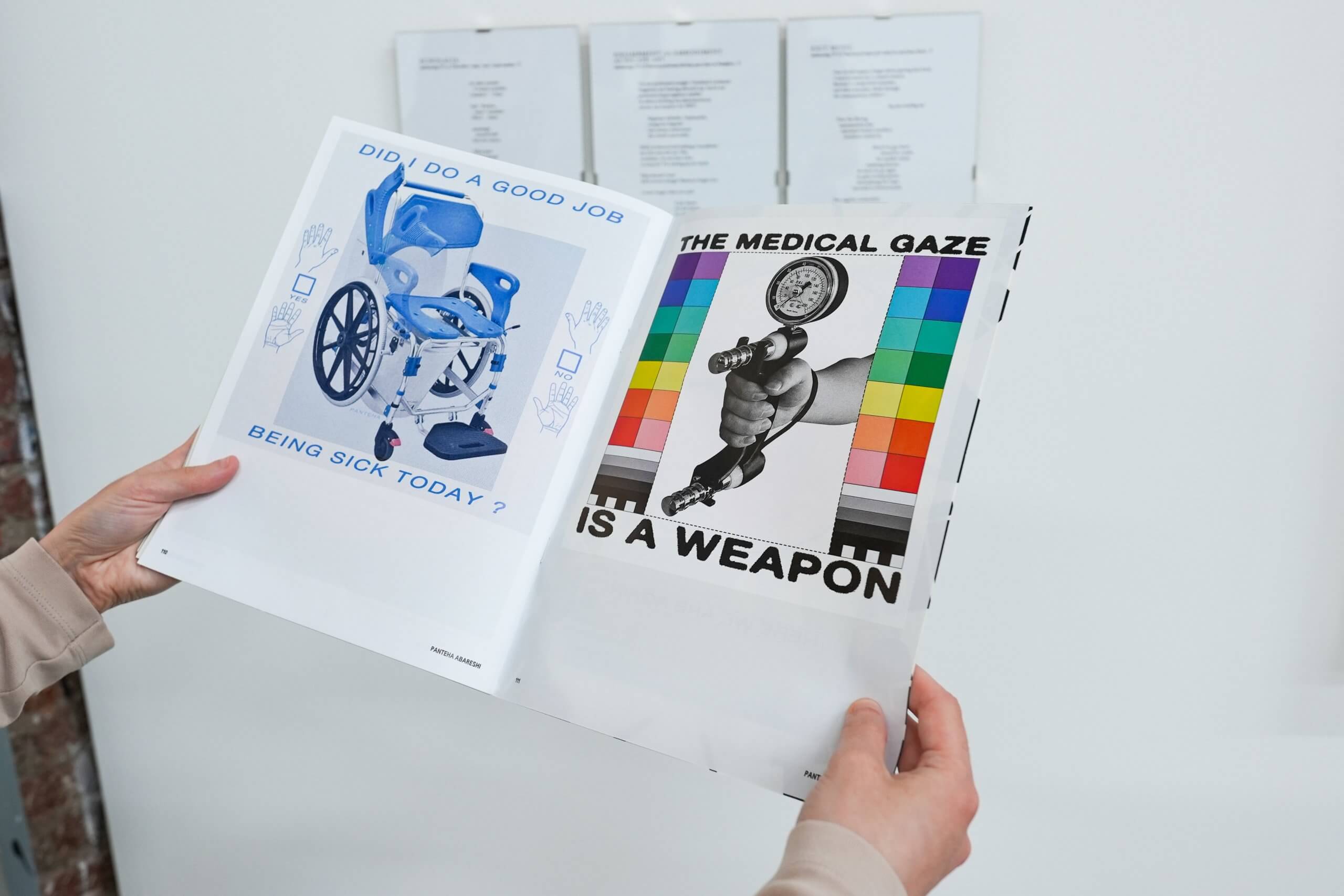 A person holds open a magazine displaying two pages: one with a wheelchair and text “Did I do a good job being sick today?”, the other with a muscle arm and “The medical gaze is a weapon.”.