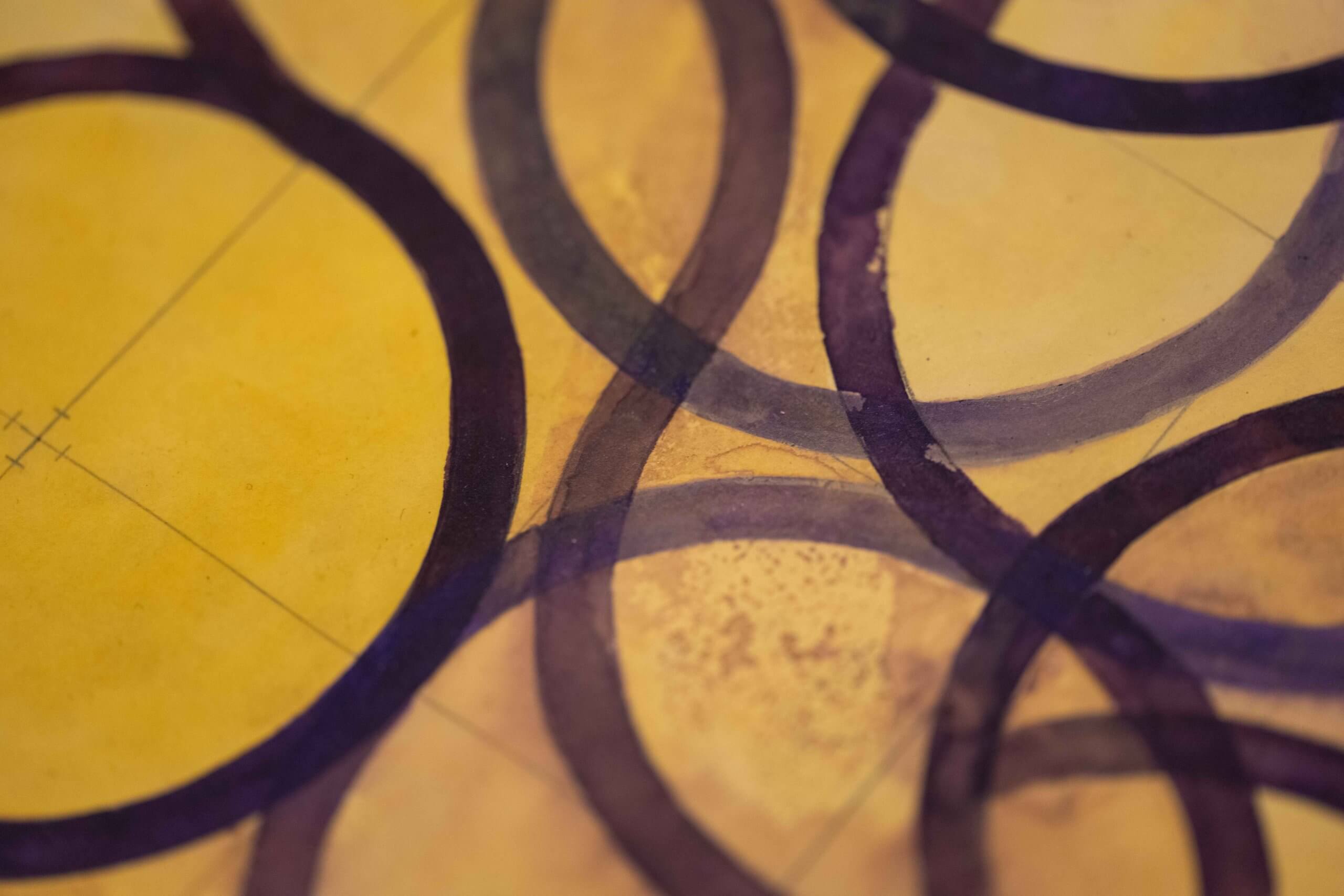 Des cercles violets translucides se chevauchent sur un fond jaunâtre et s'entrecroisent pour former des formes et des motifs variés.