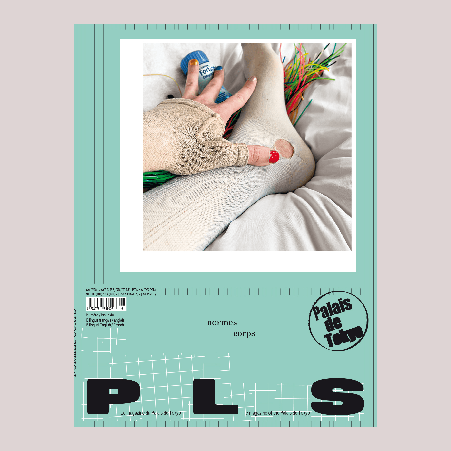 A person with two bandaged fingers, one red and one beige, holds a blue spray can while wearing beige clothing with a hole at the knee. Bright cords are visible in the background.