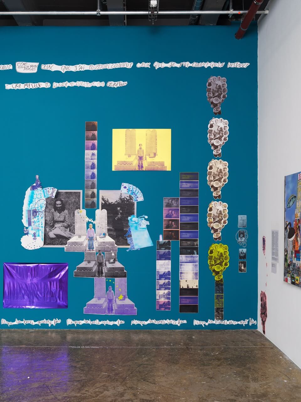 Un mur-galerie présente un fond bleu sur lequel se détache un collage de photographies, d'images imprimées colorées et de formes abstraites, disposées selon une installation artistique mêlant différentes techniques.