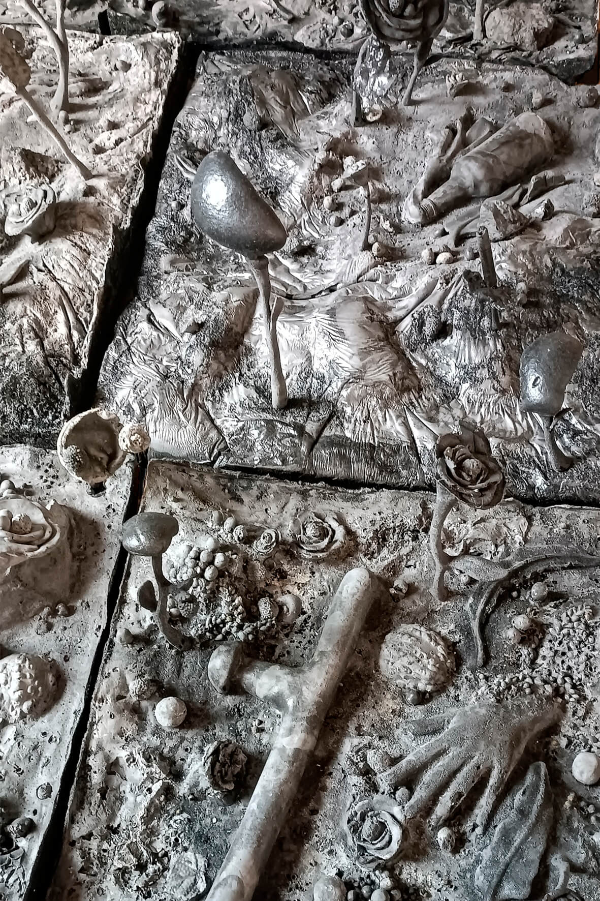 Cette œuvre d'art en relief métallique très détaillée présente diverses formes, objets et textures abstraits disposés sur une série de panneaux carrés.