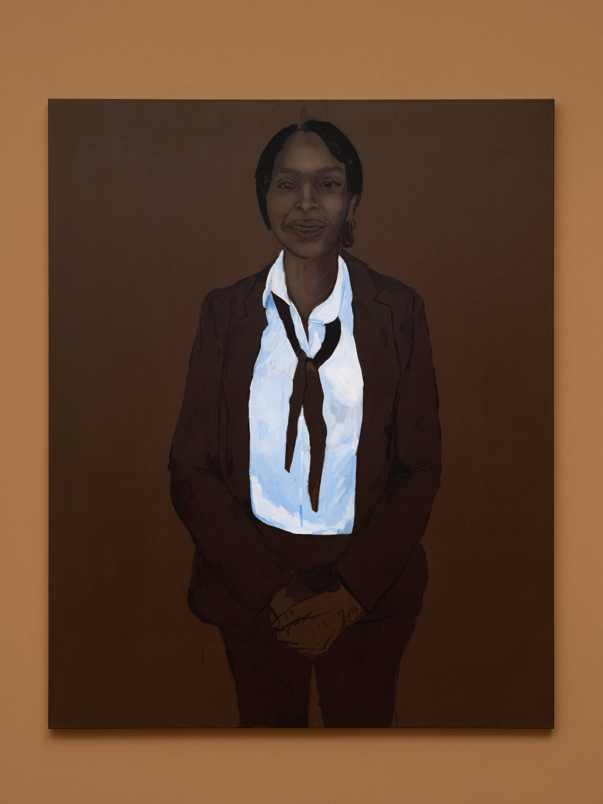 Tableau représentant une personne vêtue d'un costume sombre, d'une chemise blanche et d'une cravate lâche, debout devant un fond marron, les mains jointes devant elle.