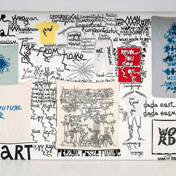 Une exposition murale de chemises et d'affiches avec des mots et des phrases écrits à la main au marqueur noir, sur les thèmes de la langue, de l'art et de la poésie, dans des styles et des tailles variés.